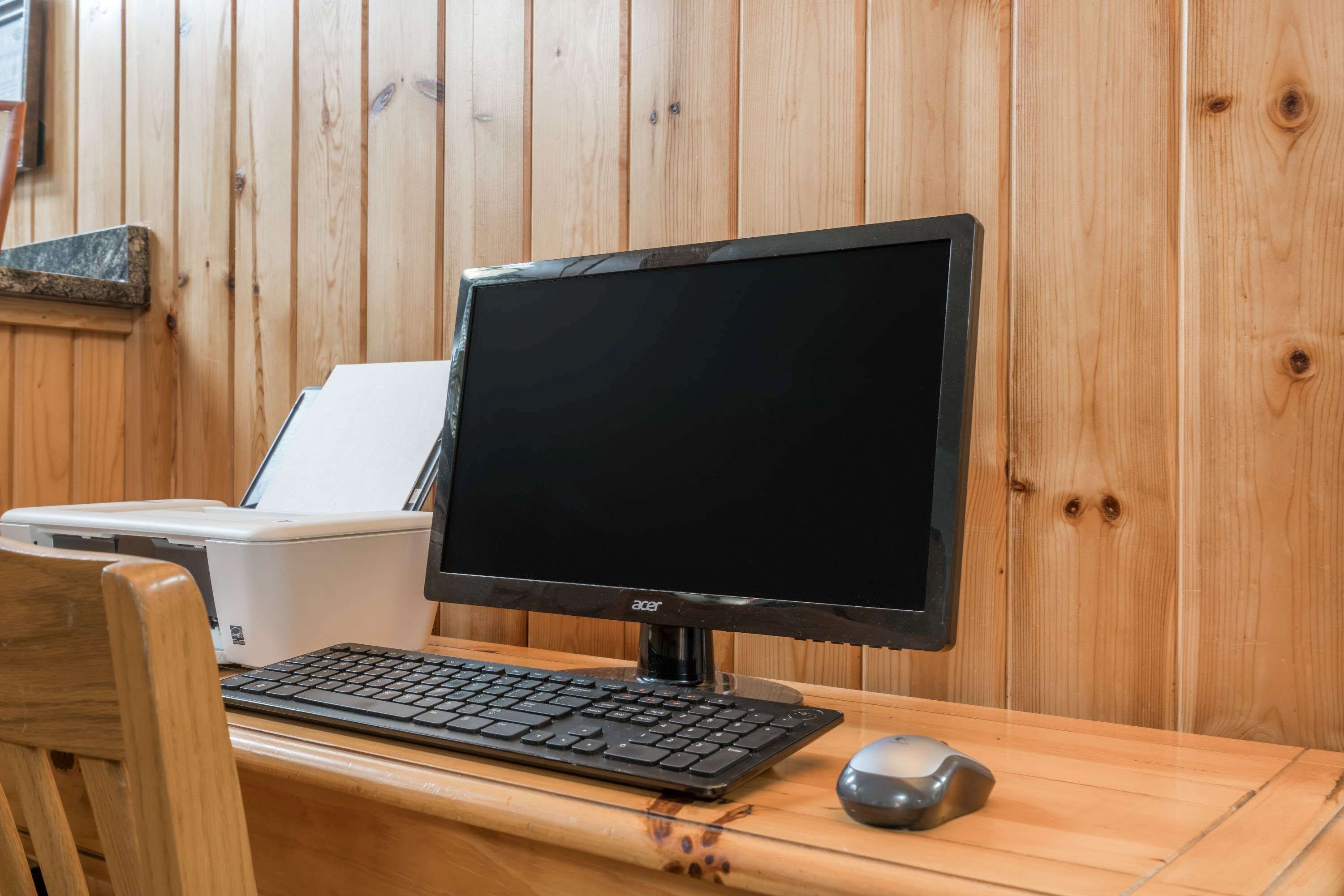 A wooden desk with a computer setup including a monitor, keyboard, and mouse.