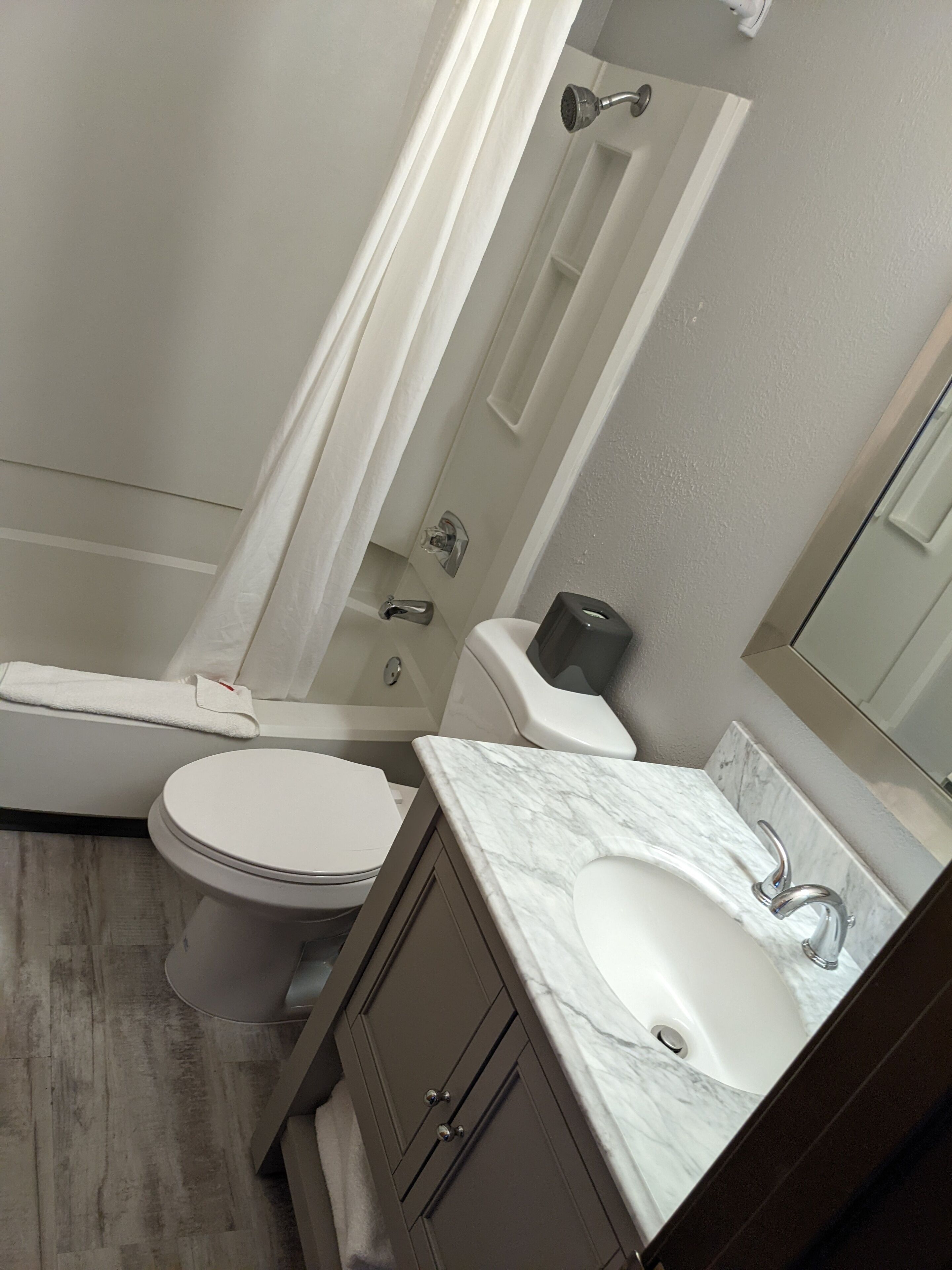 A bathroom with a toilet, sink, shower, and a towel rack.