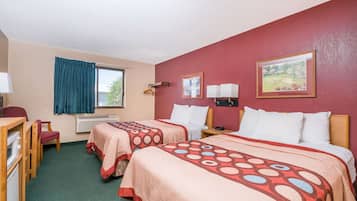Ett hotellrum med två sängar, ett skrivbord och en stol. Det finns två väggmonterade lampor och ett fönster med en gardin.