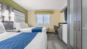 Habitación de hotel con dos camas, un escritorio, un armario y una ventana con persianas.