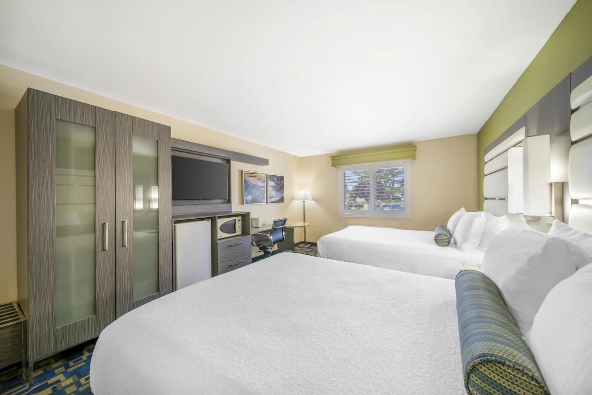 Habitación de hotel con dos camas, un escritorio, televisor y minibar.