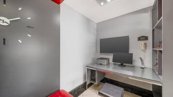 A modern office space with a desk, computer, and a red chair.