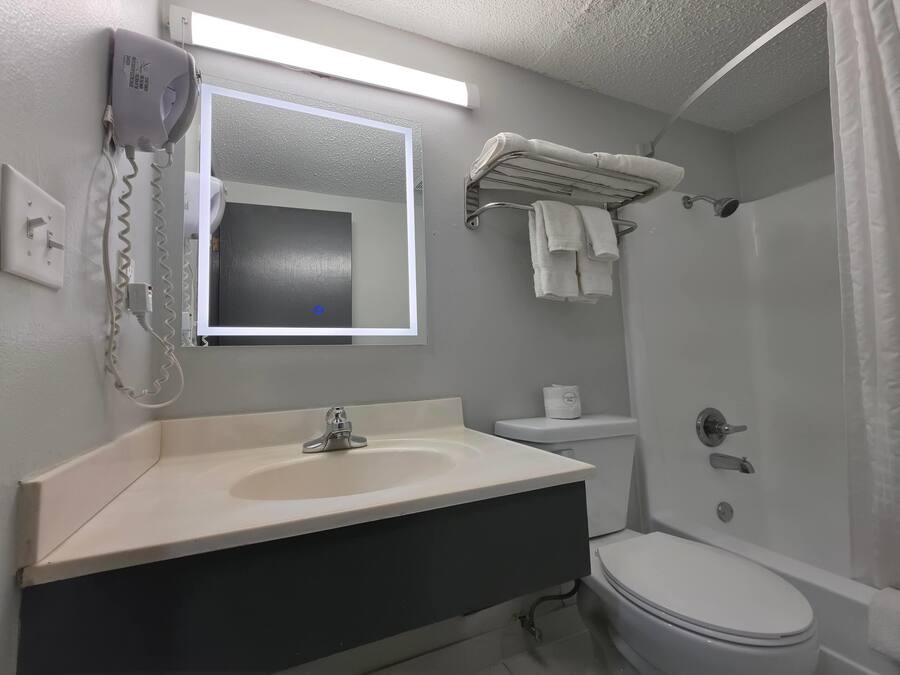 A bathroom with a sink, mirror, towel rack, toilet, and shower curtain.