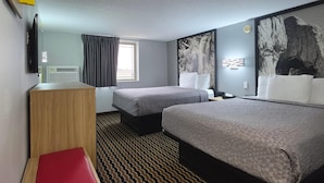 A hotel room with two beds, a desk, a TV, a window with curtains, and artwork on the walls.