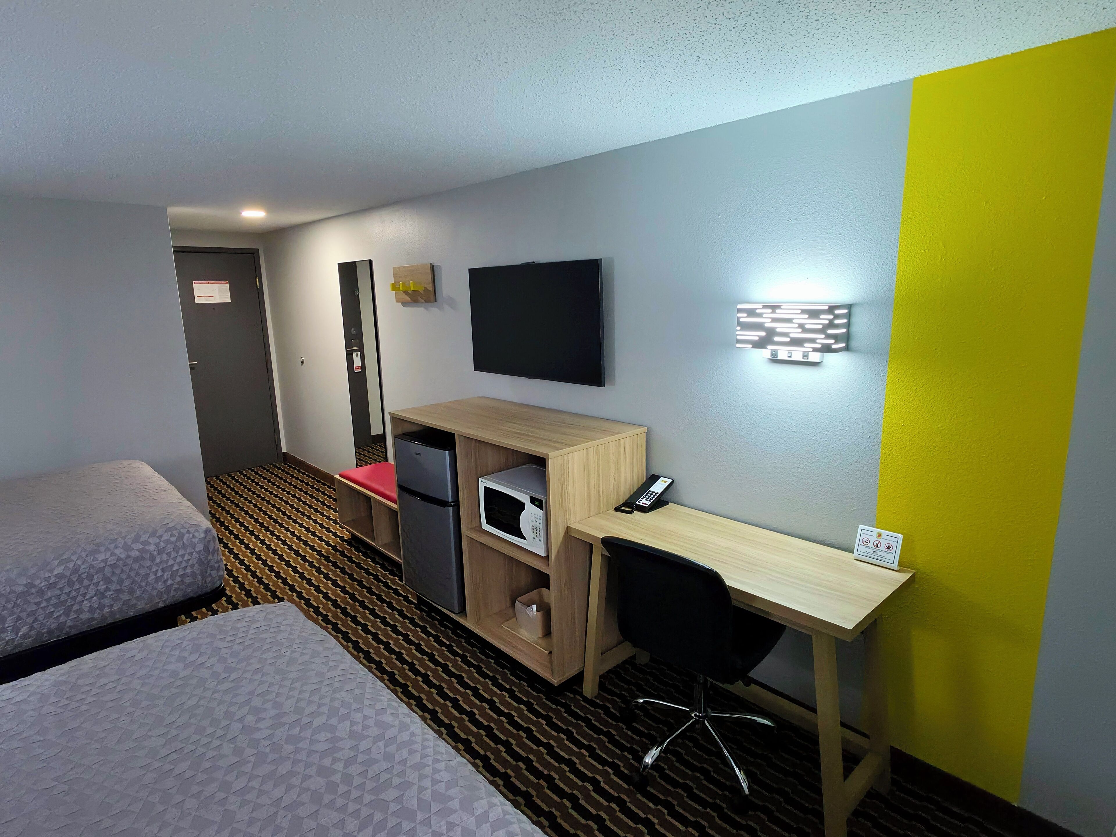 A hotel room with two beds, a desk with a computer, a microwave, and a telephone.