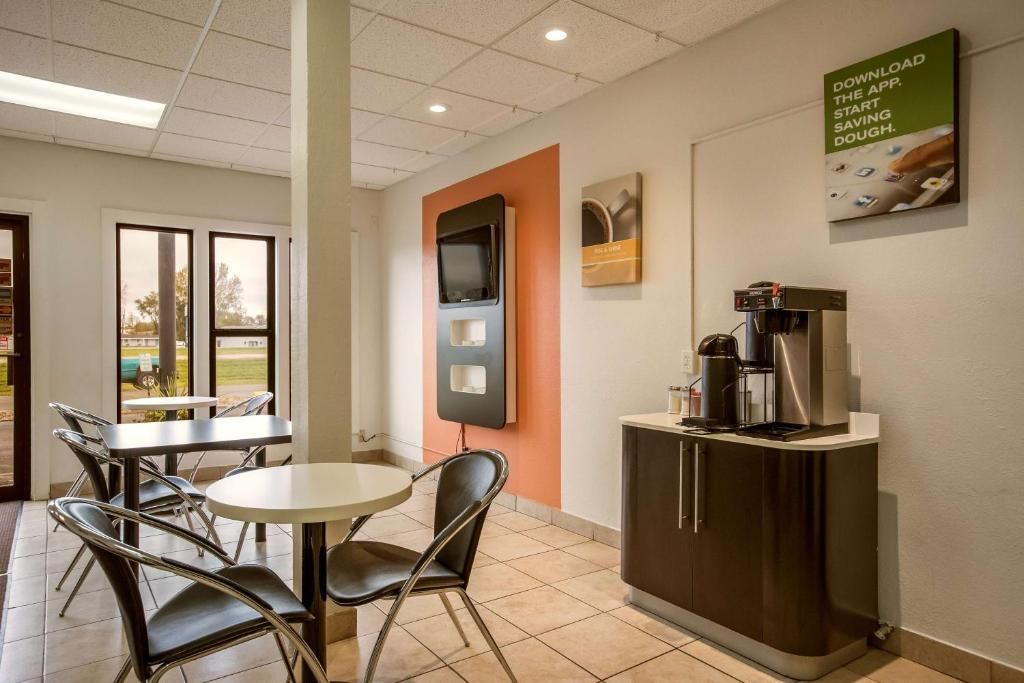 Un intérieur moderne comprenant un coin café, un espace salon et un écran fixé au mur.
