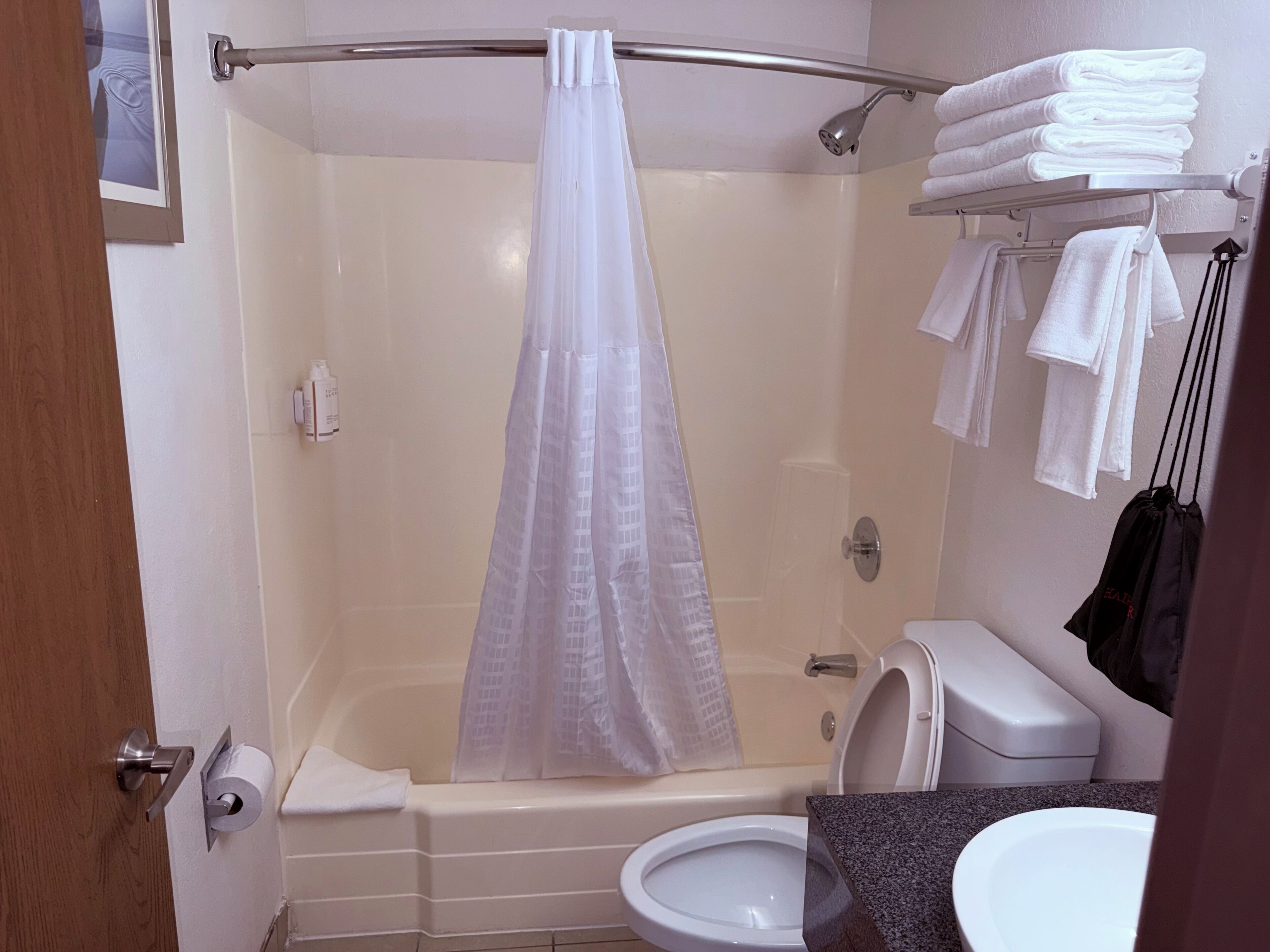 A bathroom with a shower curtain, a toilet, a sink, and a towel rack with towels.