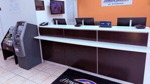 A reception desk with a clock, a monitor, and a sign for Howard Johnson by Wyndham. - Motel 6 Albert Lea (Albert Lea)
