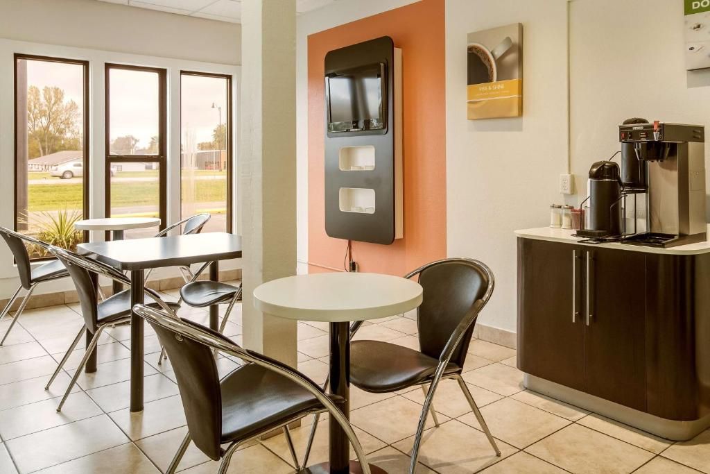 Un comedor moderno con una mesa y sillas blancas, una cafetera y una barra con dispensador de café.