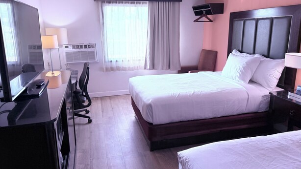 A hotel room with a bed, bedside table, desk with a lamp, chair, TV, and an air conditioning unit. - Motel 6 Albert Lea (Albert Lea)