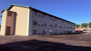 A multi-story building with a flat roof, large windows, and a parking lot in front. - Motel 6 Albert Lea (Albert Lea)