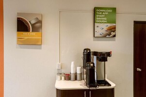 Una estación de café con una cafetera, tazas y un cartel promocionando una aplicación de café.