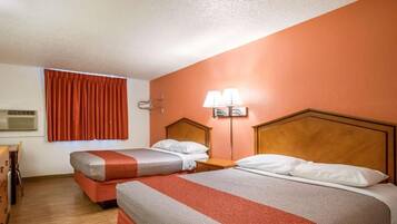 Een hotelkamer met twee bedden, een bureau en een raam met gordijnen.