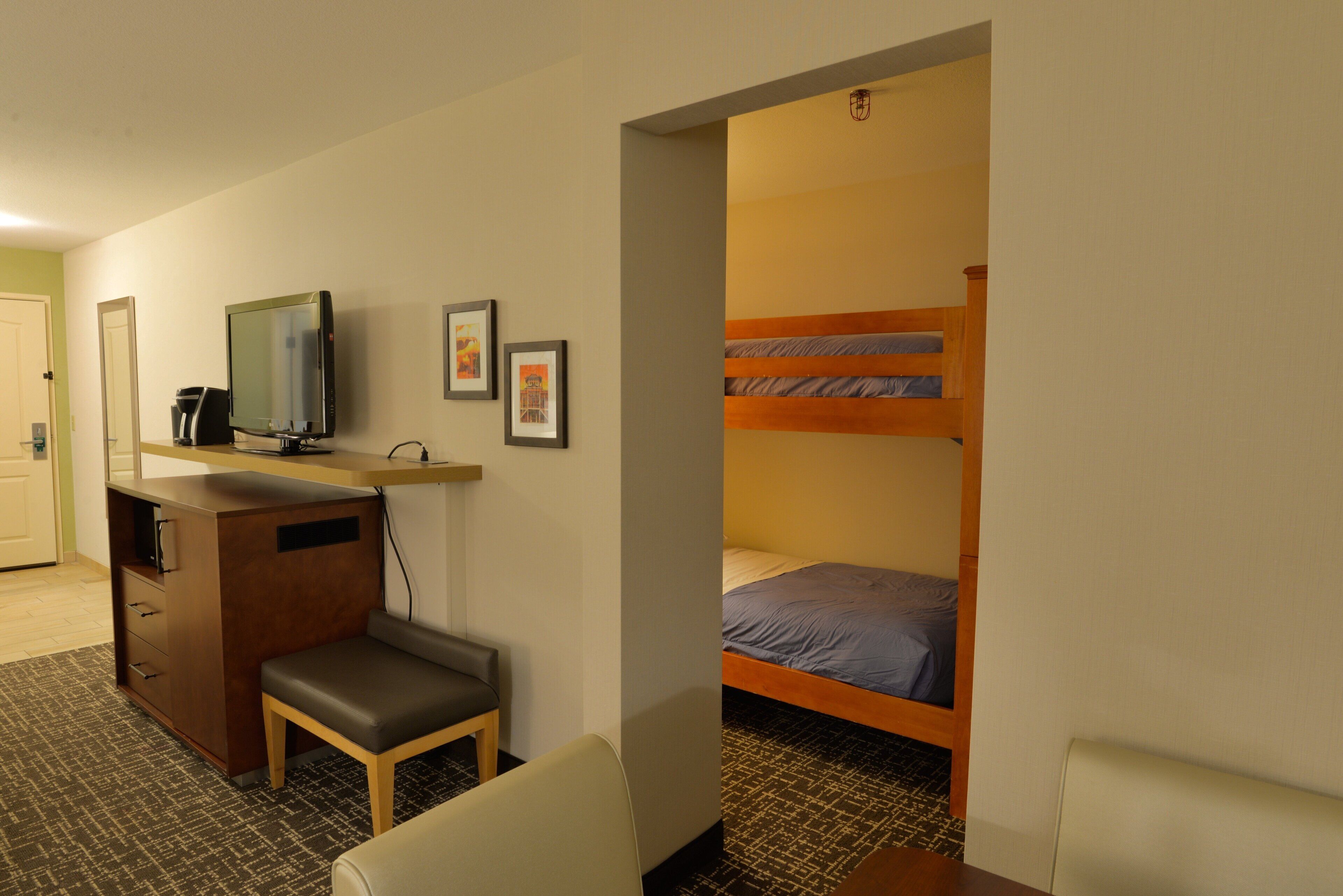 Une chambre d’hôtel équipée d’un bureau, d’une télévision, d’un lit superposé et d’un petit coin salon.