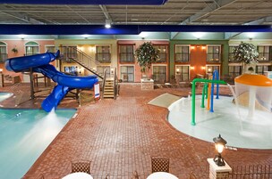 An indoor water park with a blue slide, a pool, and a play area with colorful structures.