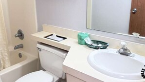 Une salle de bain équipée d’une baignoire, de toilettes, d’un lavabo et d’un miroir au-dessus du lavabo.