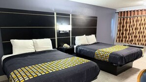 Une chambre d’hôtel avec deux lits, une table de chevet, une lampe et un rideau.