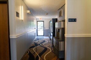 Un couloir d’hôtel avec un panneau indiquant la sortie, un réfrigérateur et des panneaux de signalisation indiquant l’emplacement des chambres.