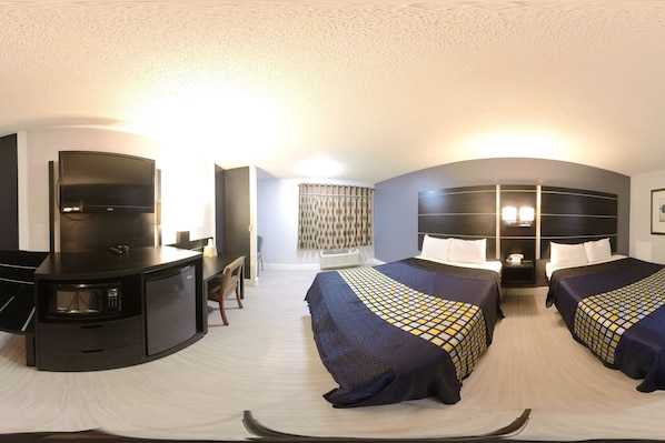 Quarto de hotel com cama, escrivaninha, frigorífico e televisão.