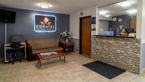 A hotel reception area with a sofa, a desk, a computer, and a reception counter.