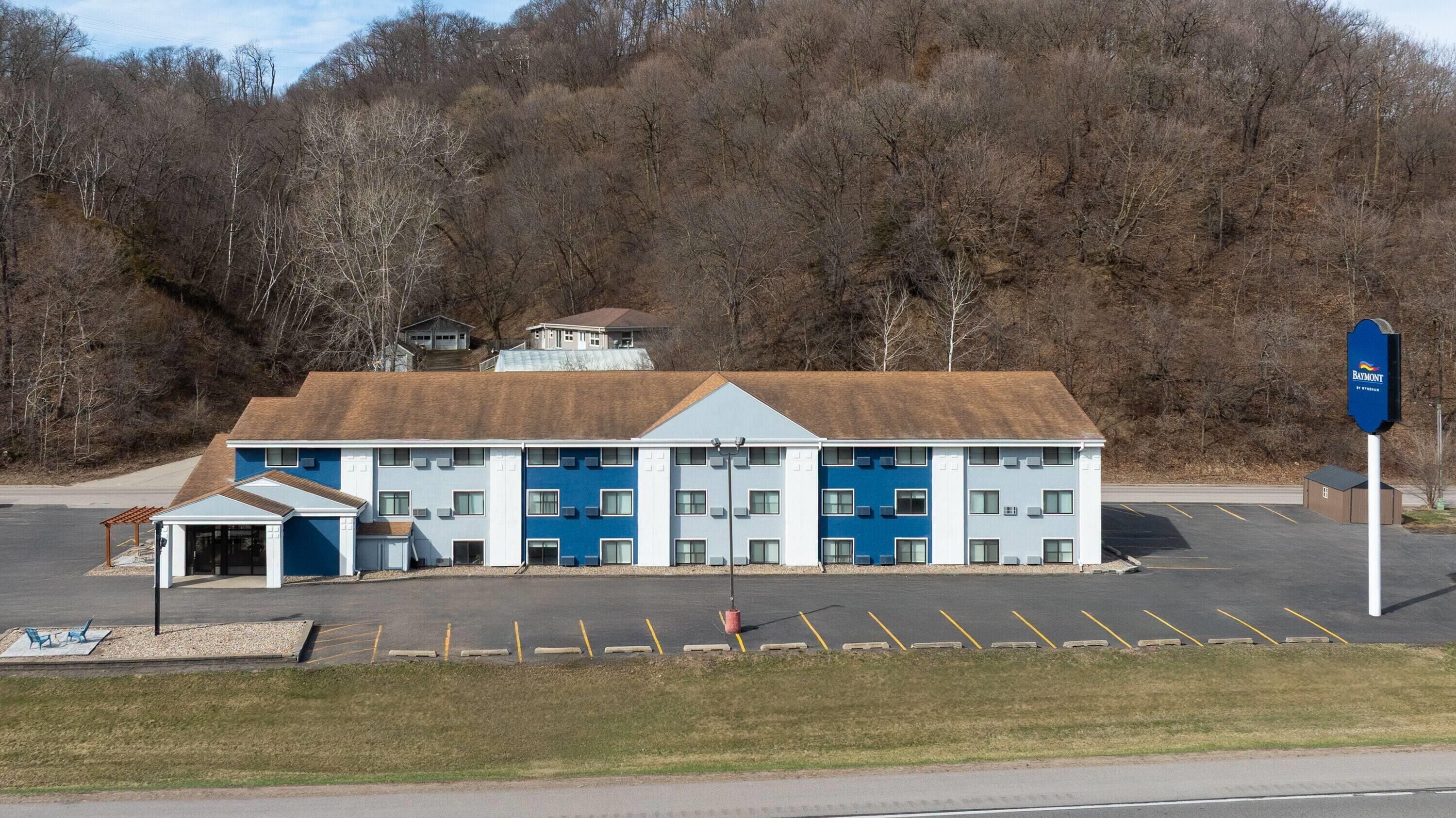 A motel with a parking lot, a covered entrance, and a sign for the brand 'Baymont.'