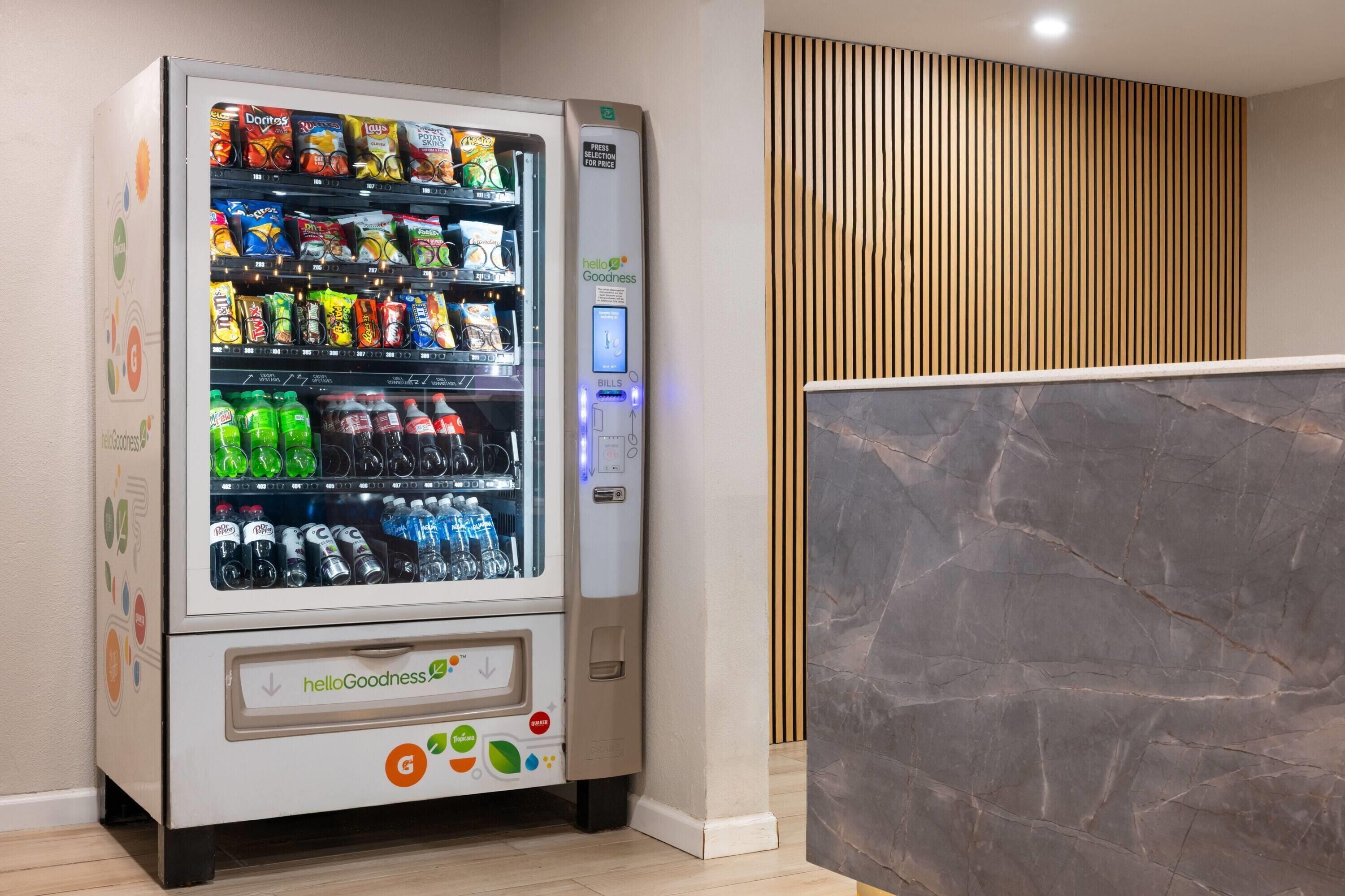 A vending machine with snacks and drinks, a HelloGoodness logo, and a payment interface.