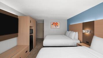 Habitación de hotel con dos camas, televisión de pantalla plana, microondas y un cuadro en la pared.