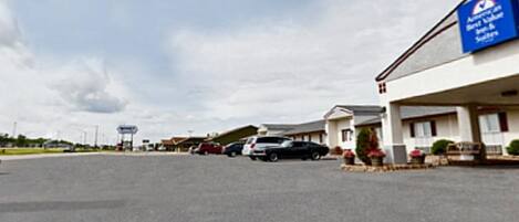 Un motel con un letrero azul, un estacionamiento y varios coches aparcados al frente.