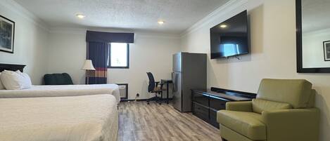 A hotel room with a bed, desk, chair, TV, and a large mirror.