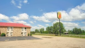 Un motel avec un toit rouge, un parking et une enseigne indiquant qu’il s’agit d’un motel Super 8.