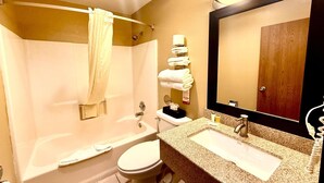 Une salle de bain avec une baignoire, des toilettes, un lavabo et un grand miroir.
