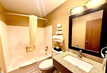 Ein Badezimmer mit Badewanne, Toilette, Waschbecken und einem großen Spiegel.. Super 8 by Wyndham Melrose