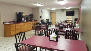 A dining area with wooden cabinets, a coffee machine, and multiple tables and chairs. - Super 8 by Wyndham St. Cloud (St Cloud)