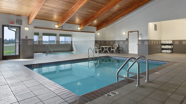 An indoor swimming pool with clear water, wooden ceiling beams, and a tiled floor. - Super 8 by Wyndham St. James (Saint James)