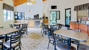 A restaurant with multiple tables and chairs, a kitchen area, and a ceiling fan. - Super 8 by Wyndham St. James (Saint James)