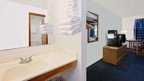 A hotel room with a sink, mirror, towels, a TV, and a small table with a lamp. - Super 8 by Wyndham St. James (Saint James)