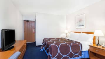 A hotel room with a bed, bedside lamps, a TV, and a wooden dresser.