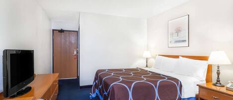 A hotel room with a bed, bedside lamps, a TV, and a wooden dresser.