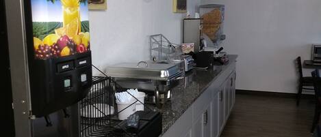 Una cocina con una cafetera, un bote de basura y un cartel que dice 'Florida's Growers' Pride'.