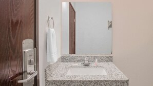 Un baño con lavamanos de encimera de granito, un espejo y un perchero para toallas.