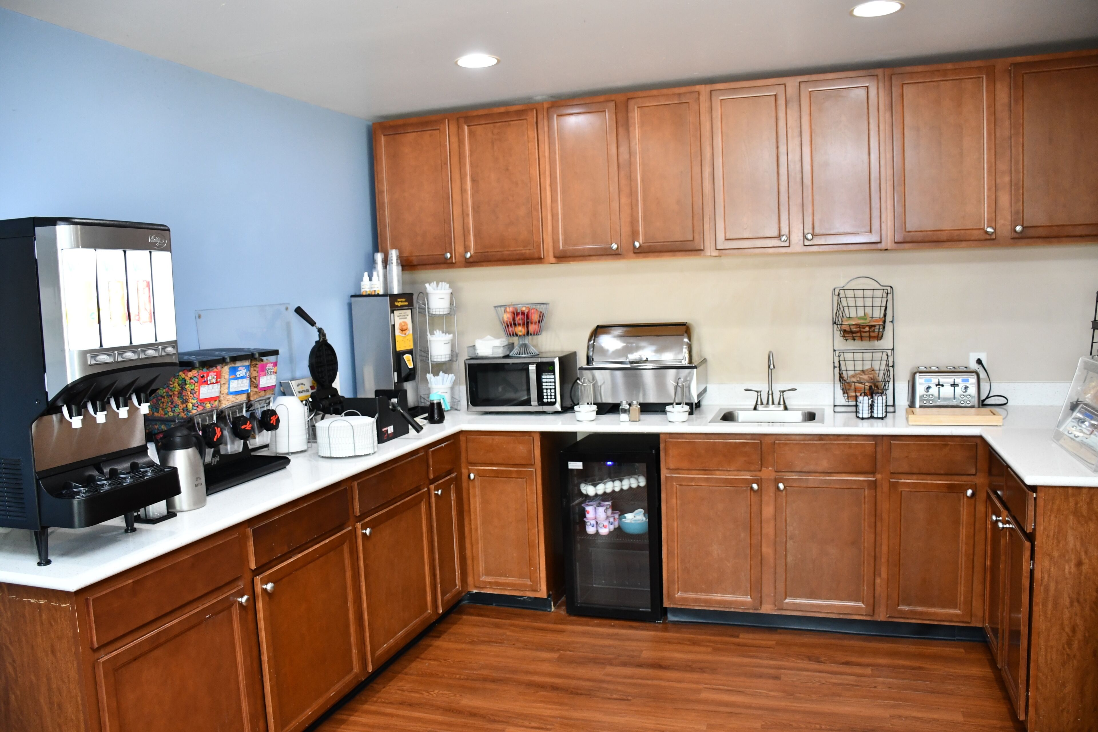 A kitchen with wooden cabinets, a coffee machine, a microwave, a toaster, and a dishwasher.