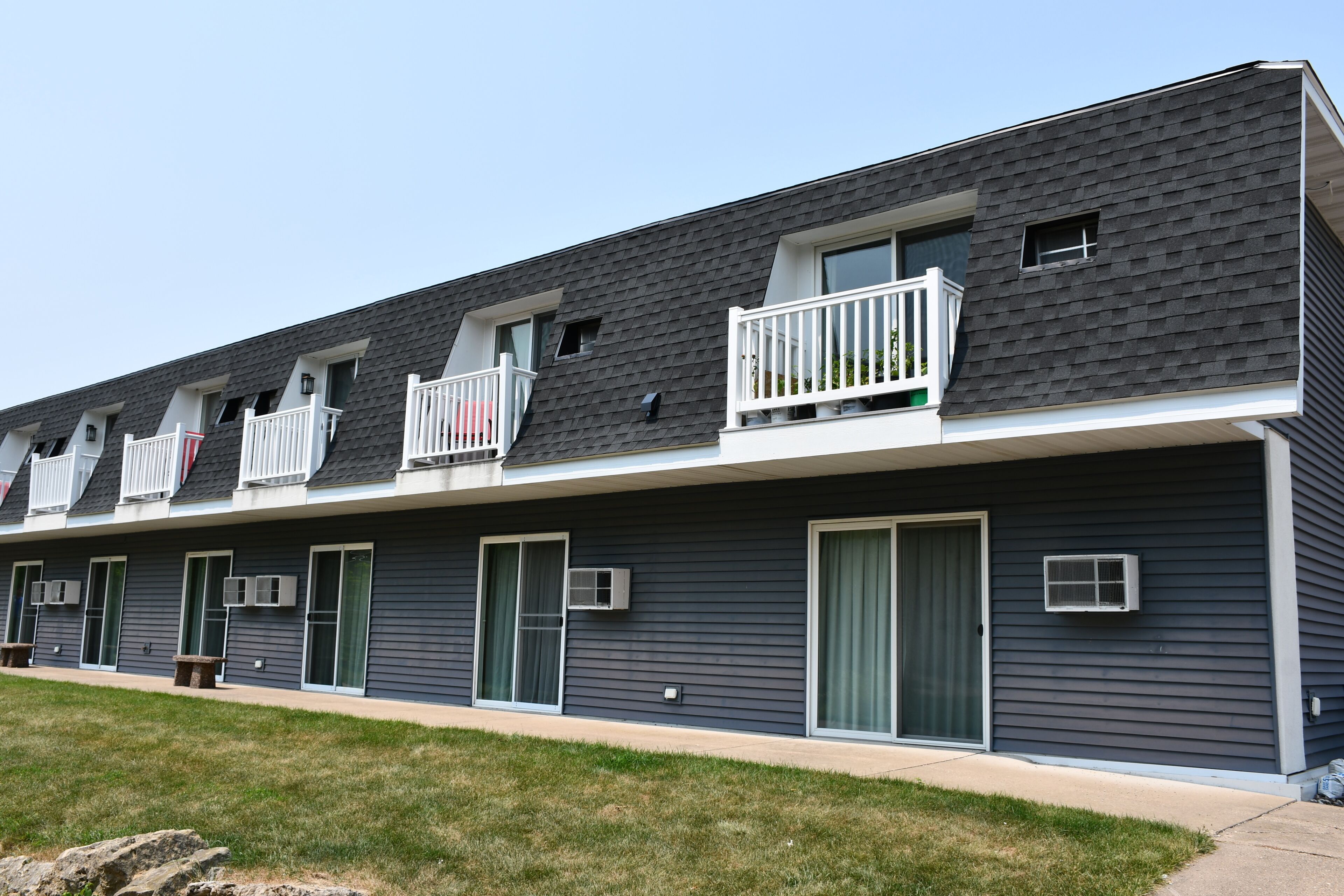 A row of townhouses with individual balconies, front doors, and small windows.