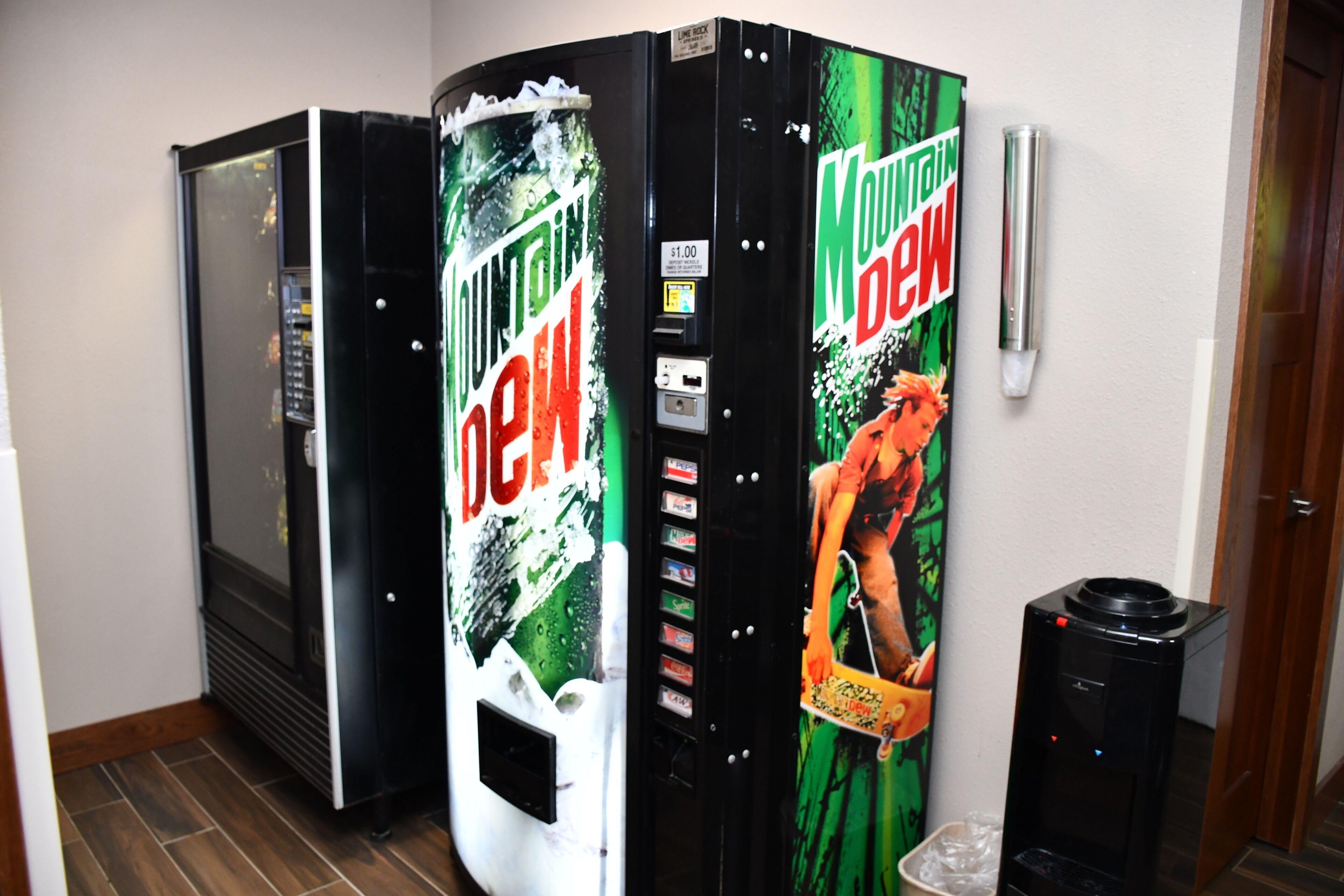 A vending machine with Mountain Dew branding and a person in a red outfit.