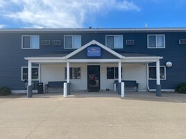 Un hotel con fachada azul, un acceso cubierto y un cartel que dice 'Baymont Inn Suites by Wyndham'.