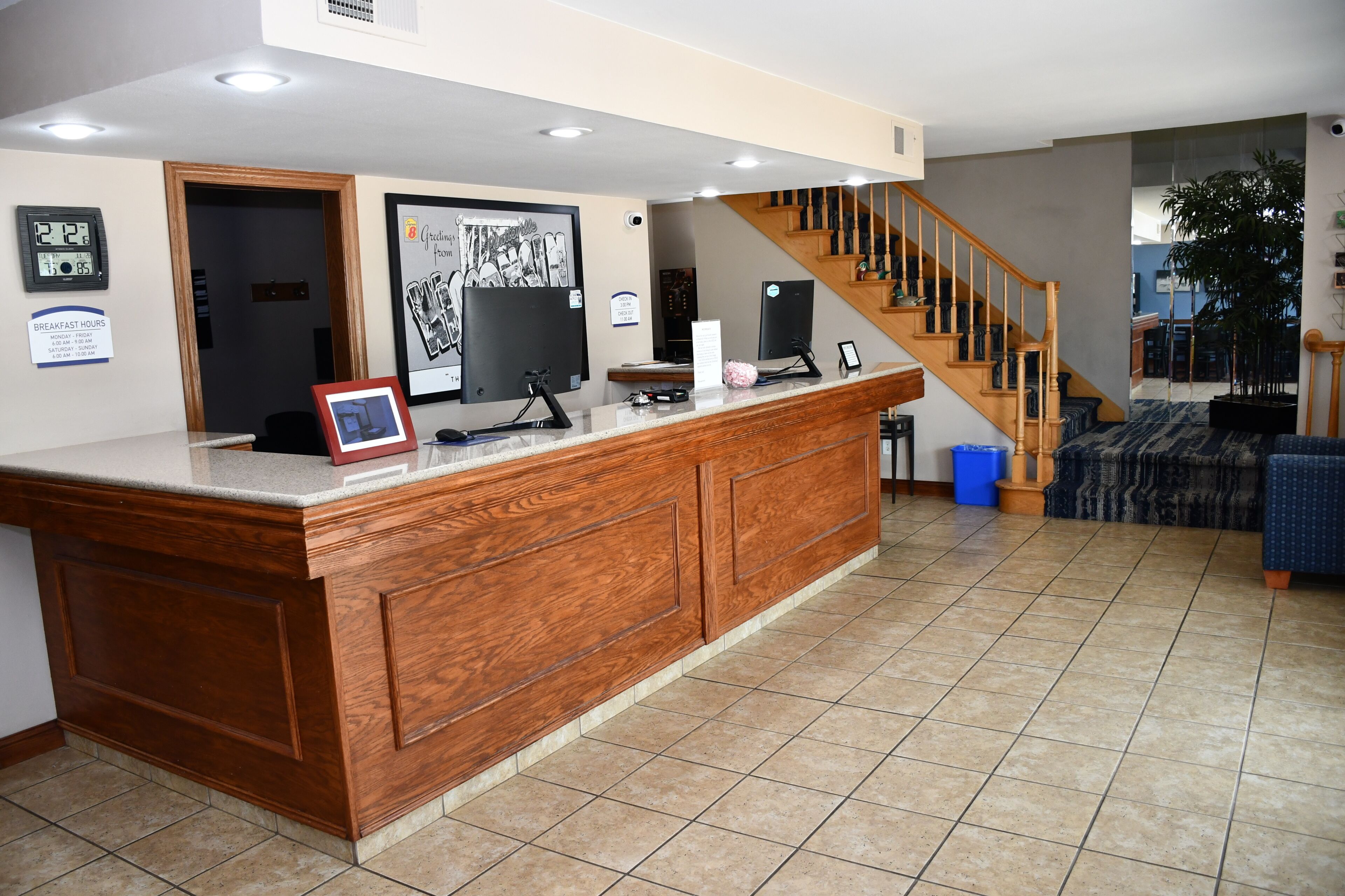 A reception desk with a clock, a framed welcome sign, and a digital clock displaying the time.