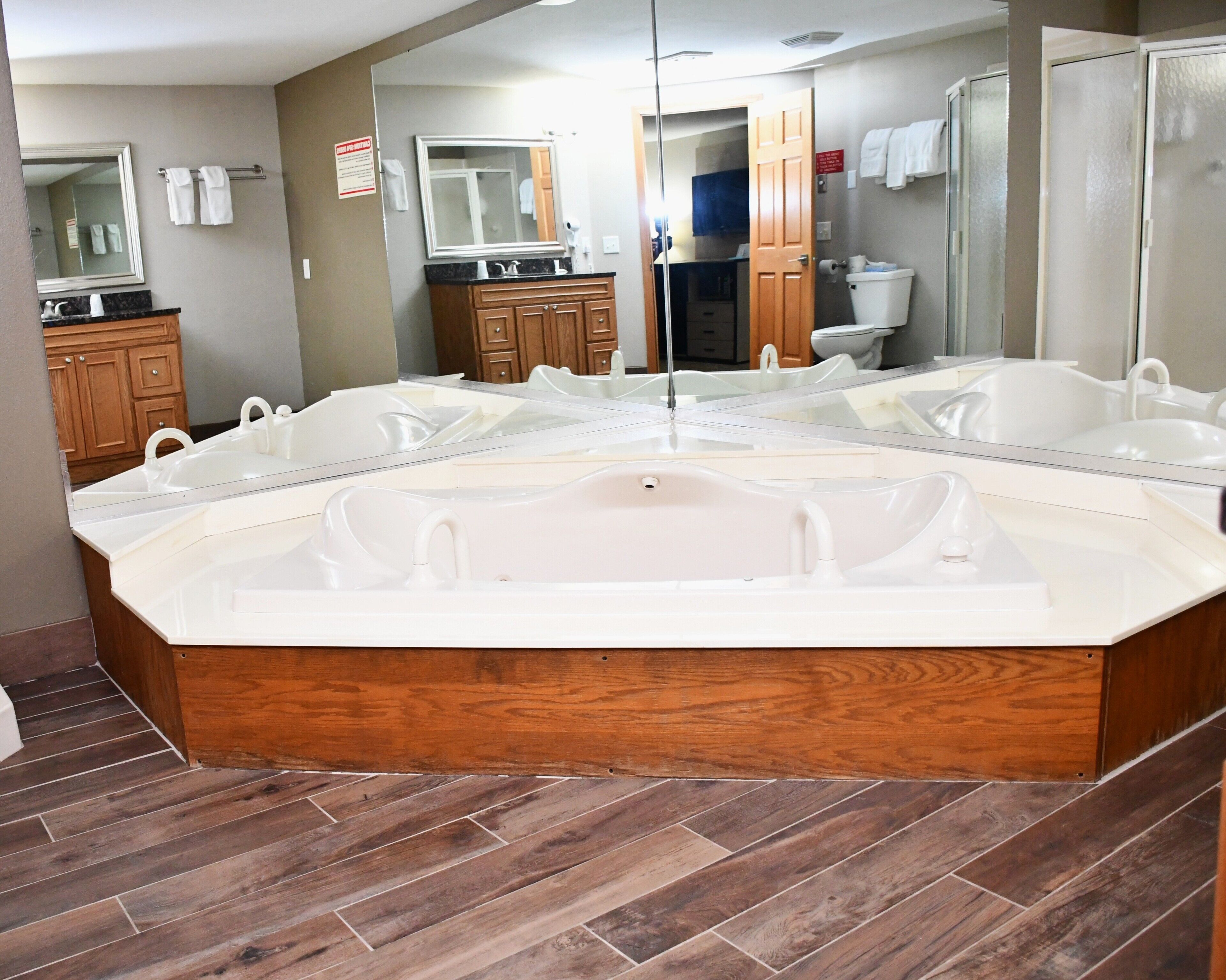 A modern bathroom with a large freestanding bathtub, wooden cabinetry, and a mirror reflecting the room.