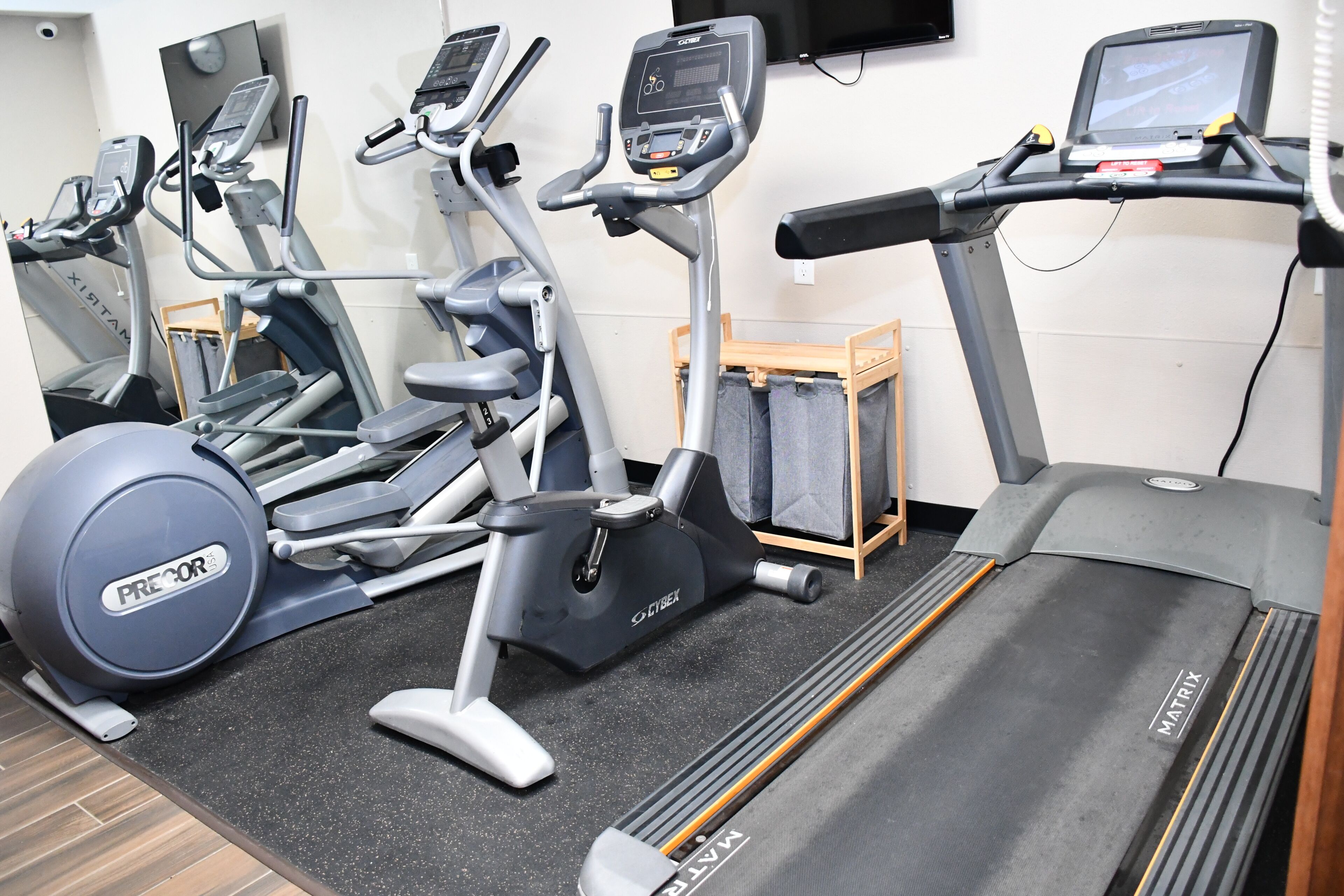 Un gimnasio con diverso equipo de ejercicio, incluyendo cintas de correr, bicicletas estáticas y una máquina de remo.