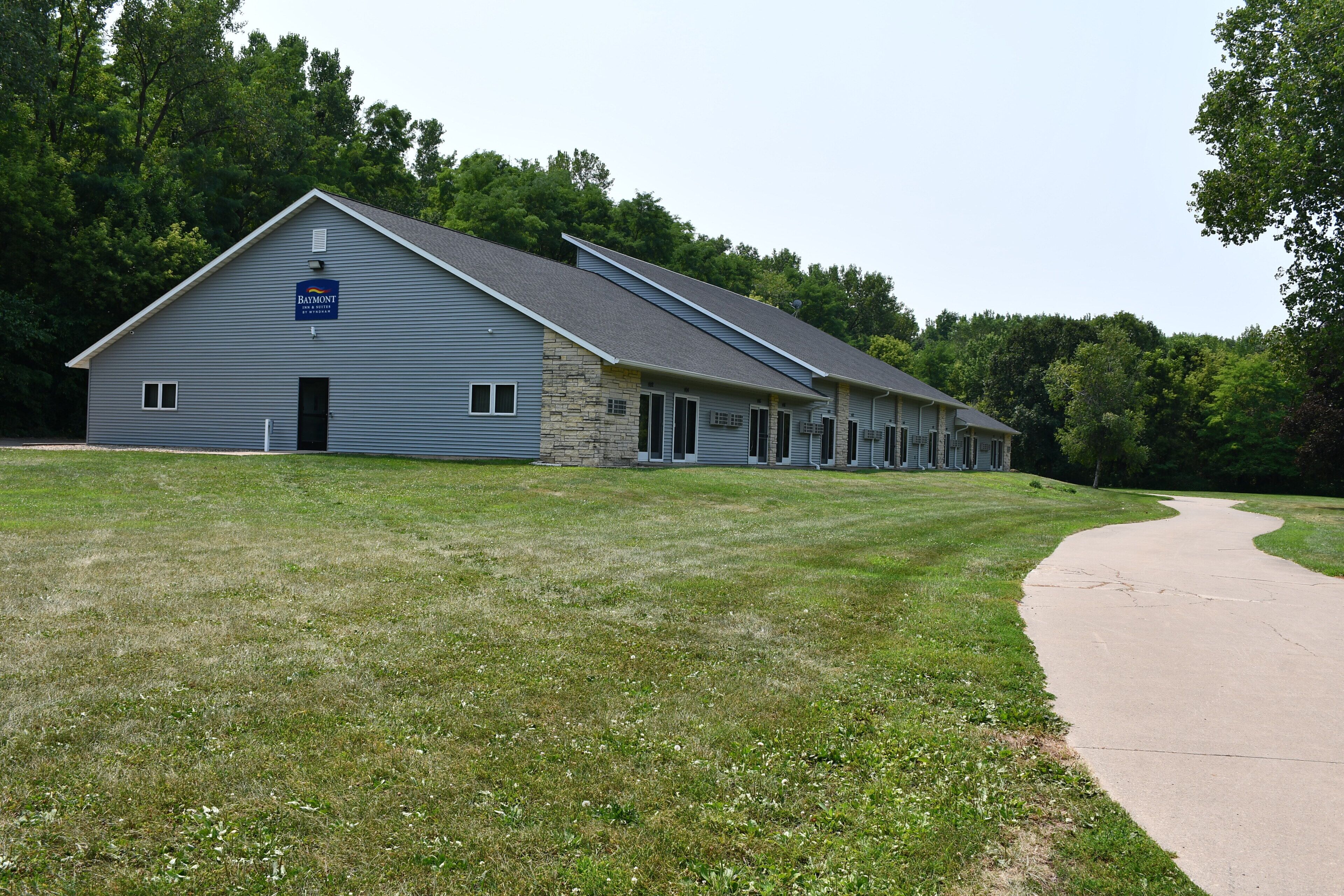 A building with a stone facade and a blue sign indicating it is a Baymont Inn & Suites.