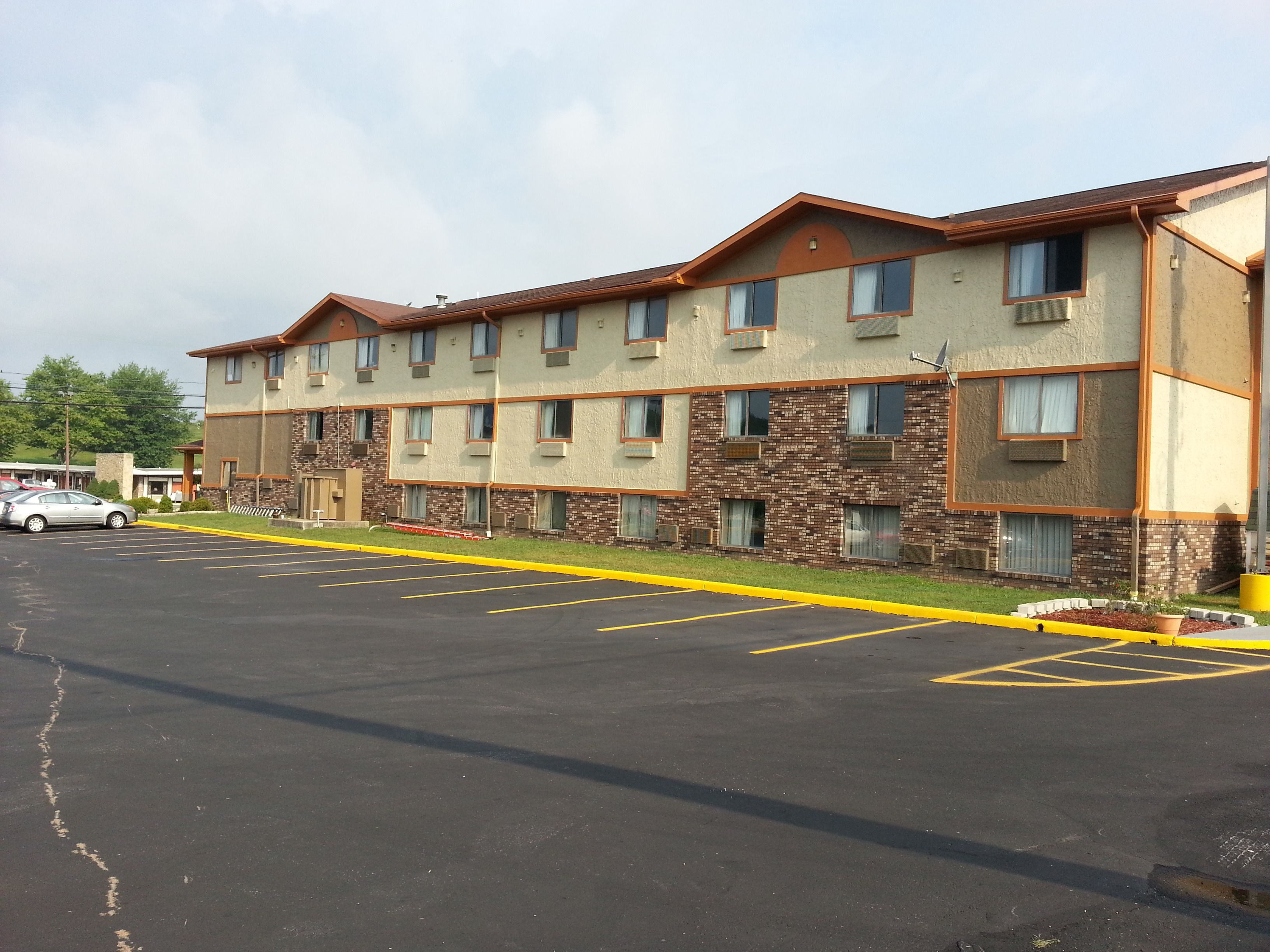 A multi-story hotel with a brick facade and a parking lot in front.