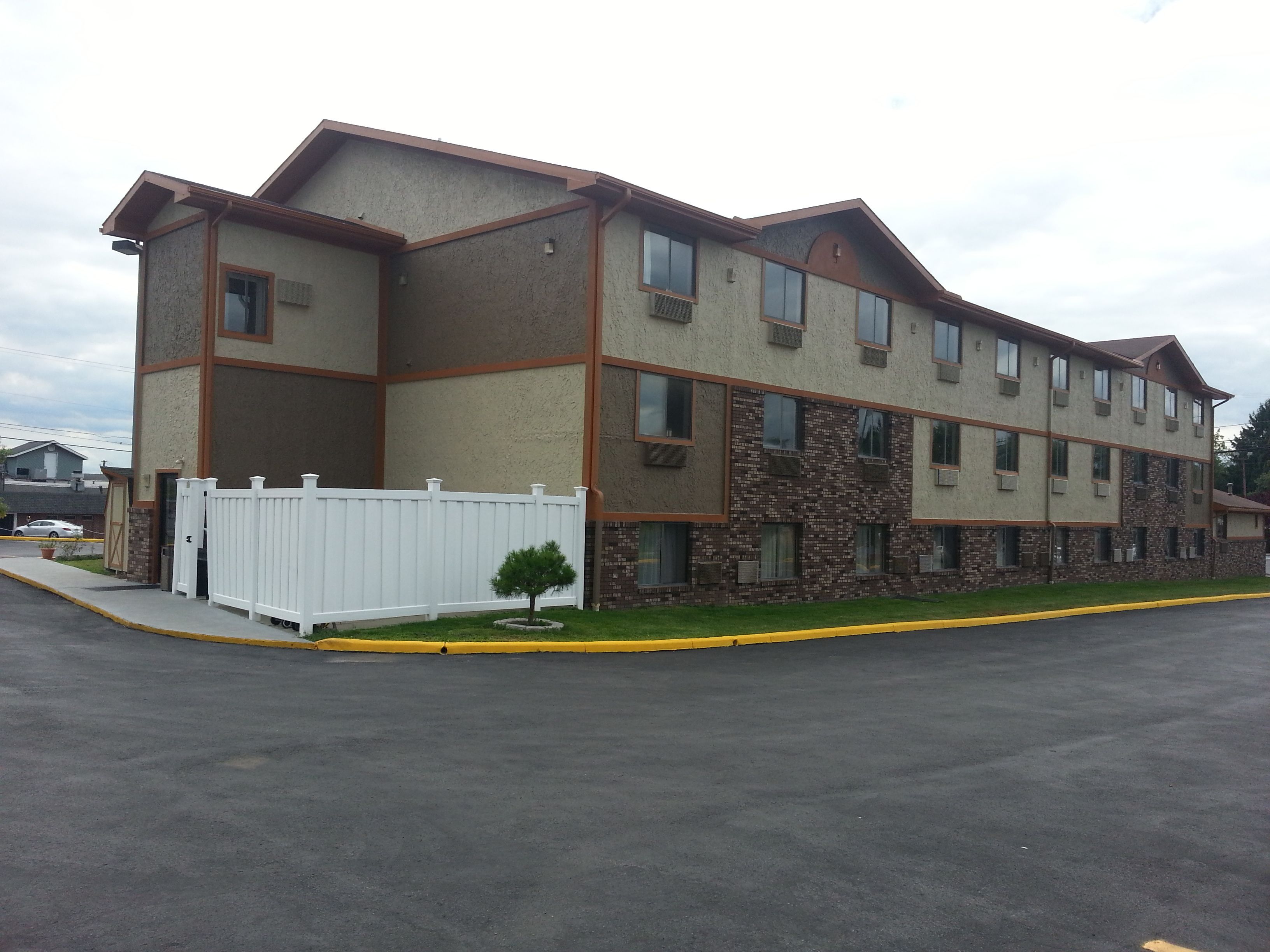 A multi-story hotel with a brick facade, multiple windows, and a white fence.
